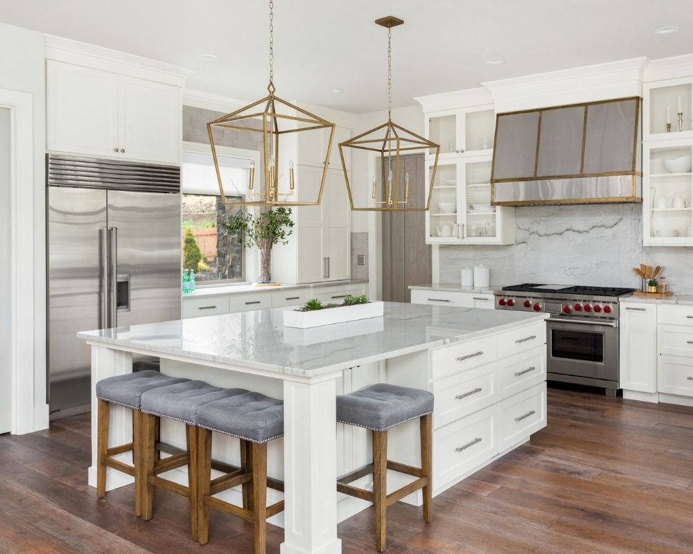 Joinery services of a white kitchen. There are some stools by the centre benchtop